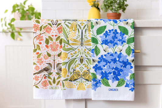 Lovely array of floral tea towels draped over a counter in a white kitchen