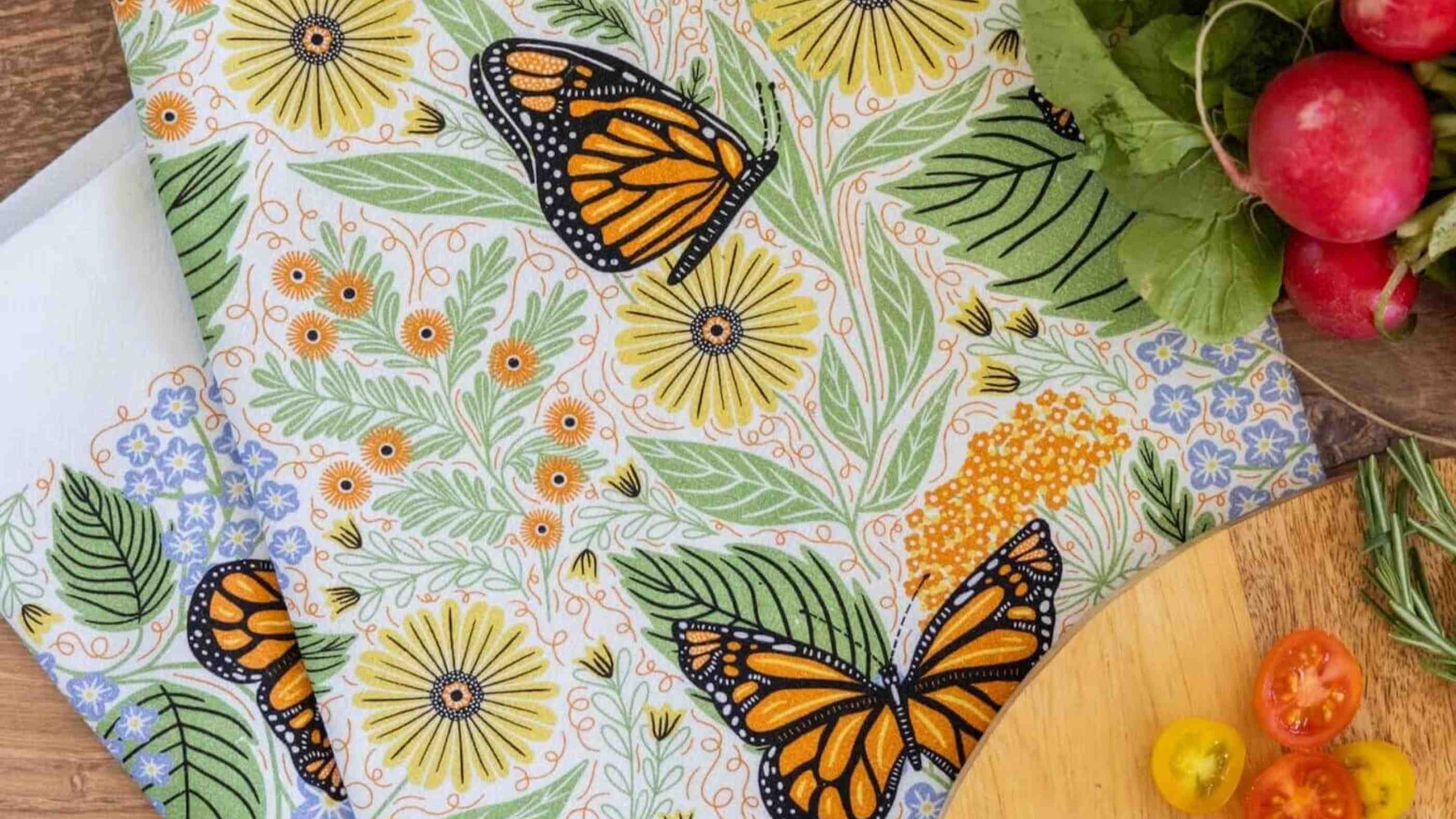 Monarch Garden tea towel by Gingiber — featuring hand-illustrated butterflies on flour sack cotton, styled as a gift on a wooden surface