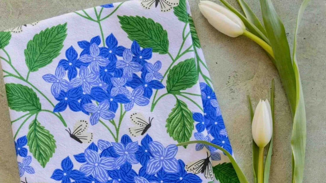 Blue Hydrangeas Botanical tea towel by Gingiber draped beside a teapot and mug as a gift for tea lovers