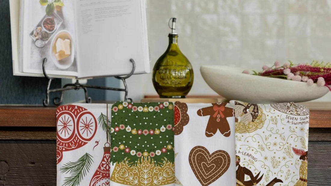 Gingiber Merry Christmas Tea Towel Bundle featuring festive owl, Christmas tree, gingerbread cookie, and 12 Days of Christmas designs displayed in a cozy kitchen.
