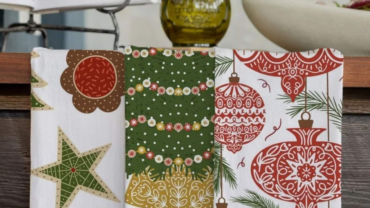 Christmas Traditions Tea Towel Bundle featuring festive cookies, a decorated Christmas tree, and red holiday ornaments displayed together in a kitchen.