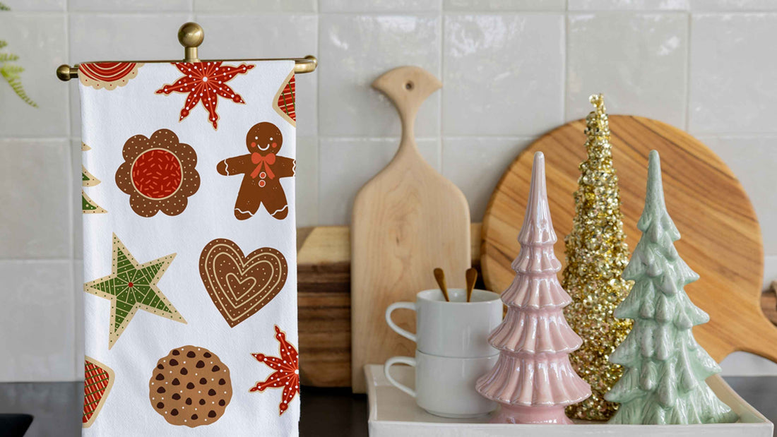 Christmas Cookies Tea Towel featuring festive gingerbread cookies, stars, hearts, and holiday treats, displayed in a cozy kitchen with colorful Christmas tree decorations for a cheerful seasonal touch.