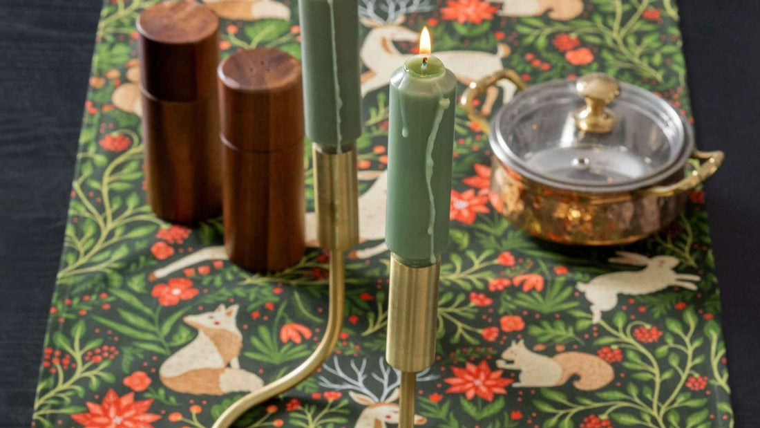 Evergreen Christmas Forest Table Runner featuring woodland animals, greenery, and red florals, styled with green taper candles and festive tabletop accents.