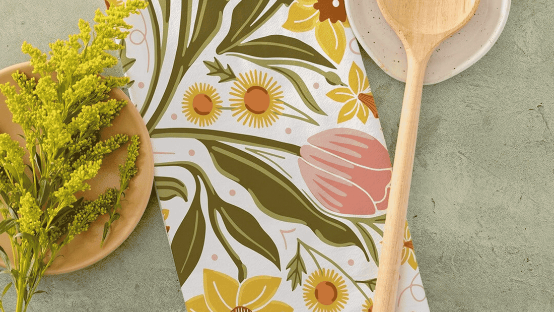 A Daffodil Dreams Tea Towel featuring hand illustrated daffodils, tulips, and leafy botanical details in soft yellow, blush pink, and green tones.