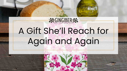 Gingiber blog banner featuring a floral tea towel with pink blooms on a kitchen counter, styled with bread and olive oil, with text “A Gift She’ll Reach for Again and Again.”