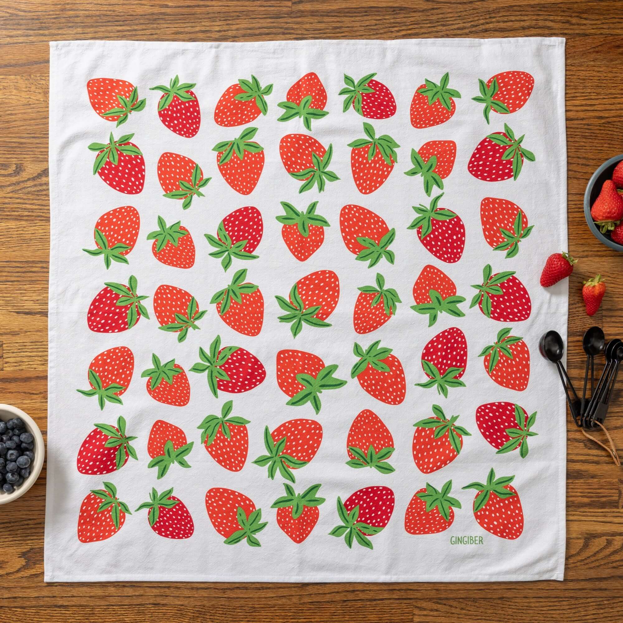 Tea towel with strawberry pattern on a wooden table