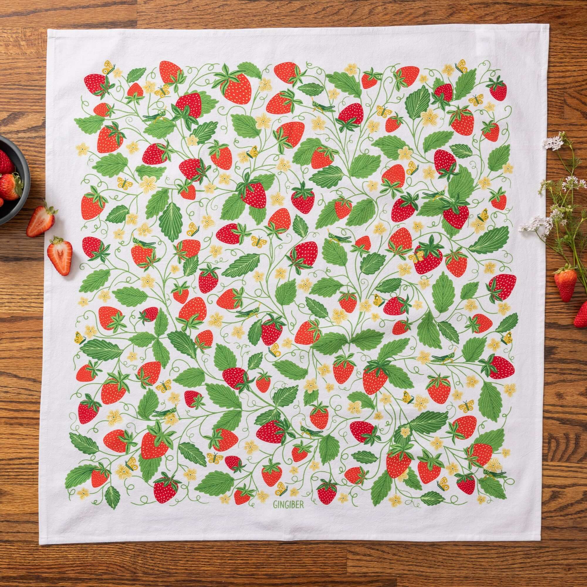 Tea towel with strawberry pattern on a wooden surface
