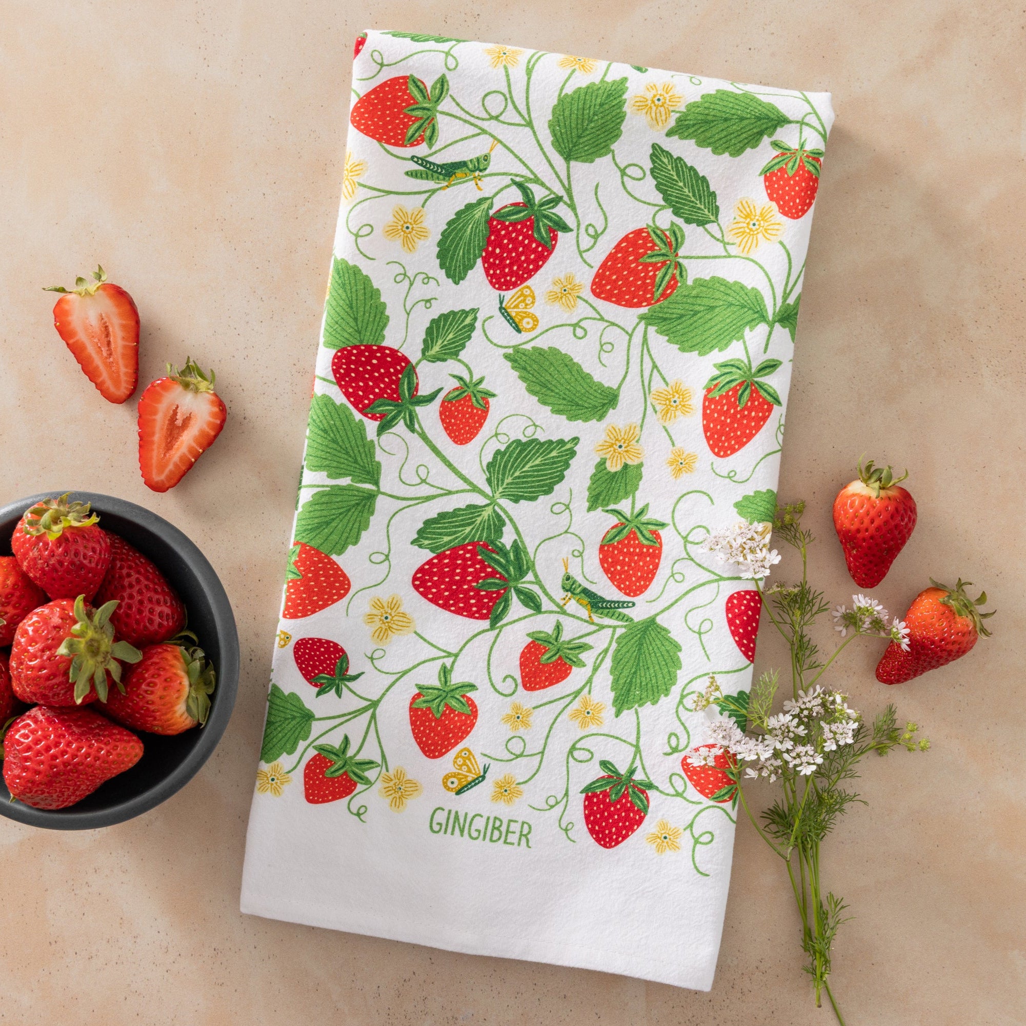 Strawberry-themed towel with a bowl of strawberries on a beige surface