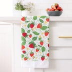 Kitchen towel with strawberry pattern hanging on a white cabinet