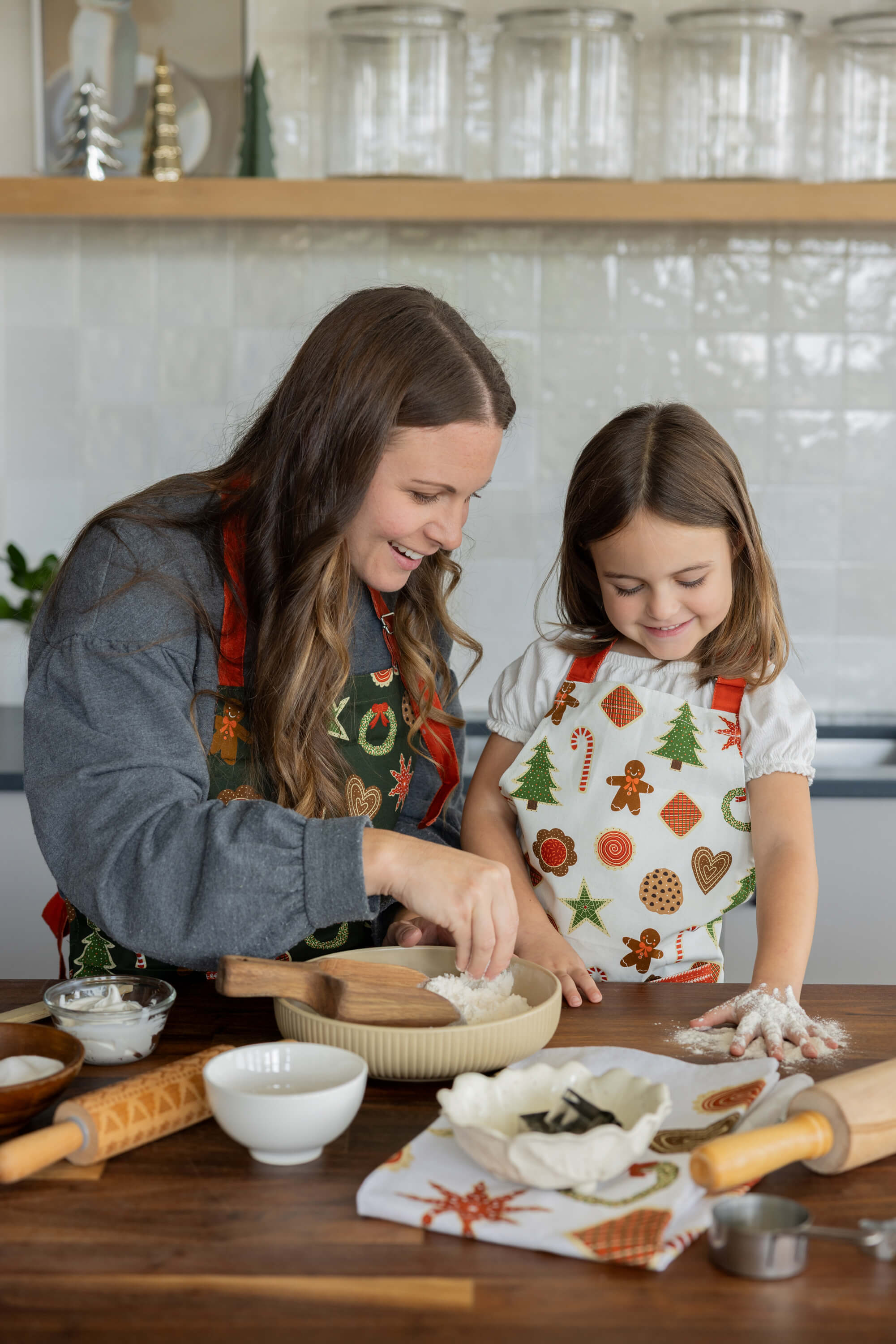 Woman and young girl in a kitchen preparing food together.