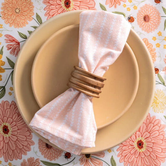 Set of plates with a floral tablecloth and bowl of strawberries on a wooden surface