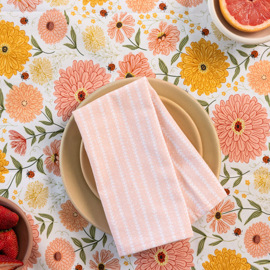 Floral placemat with a plate, napkin, and fruit on a wooden table