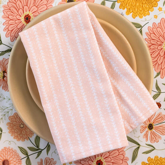 Table setting with a floral tablecloth, plates, and a striped napkin.
