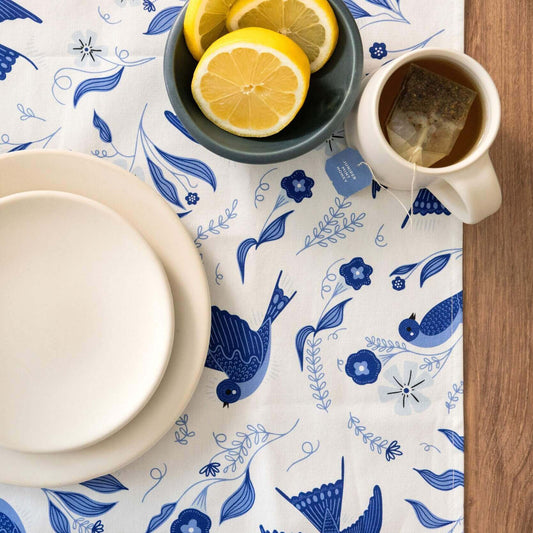 Table setting with a blue and white patterned tablecloth, lemon slices, and a teacup.