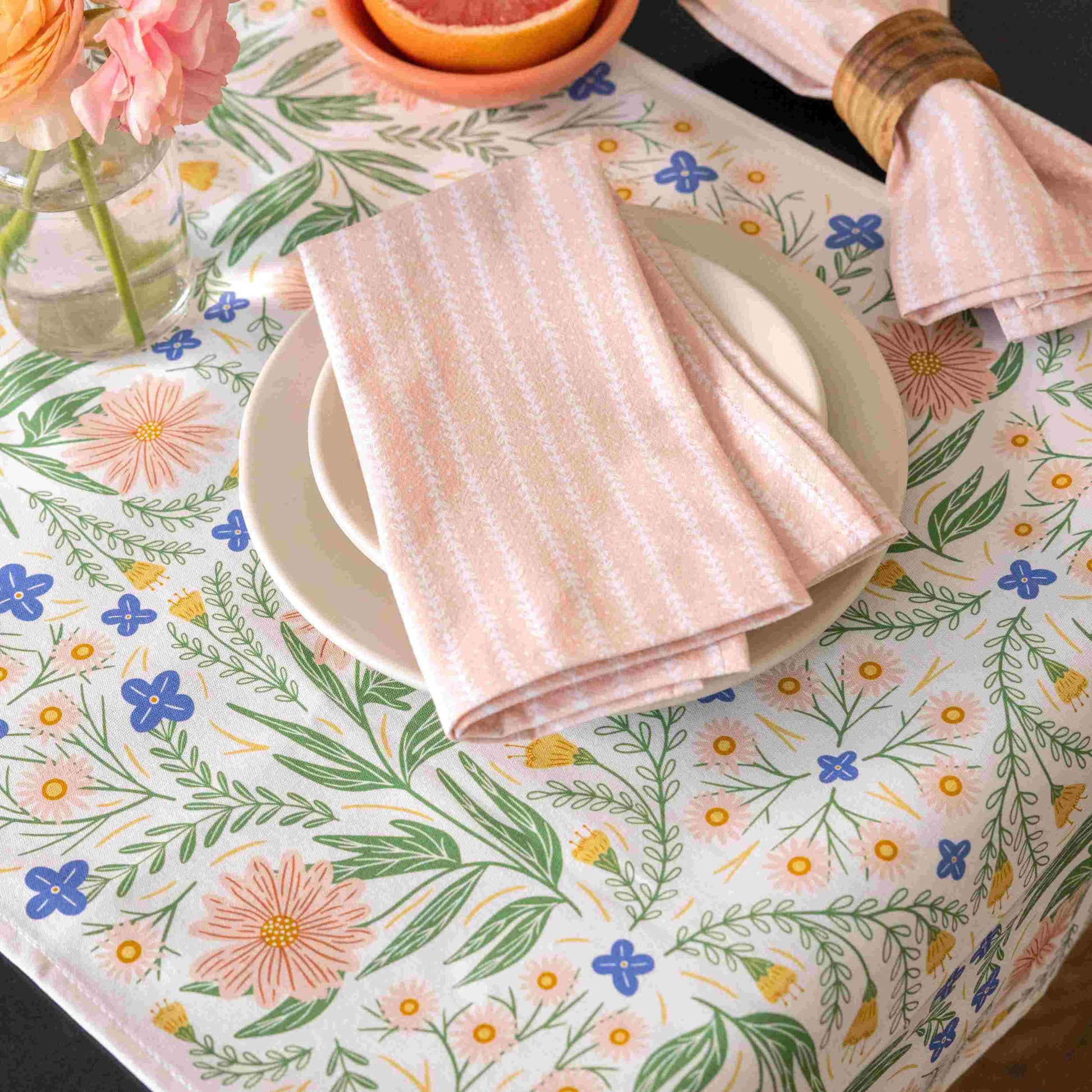 Table setting with floral tablecloth, plates, and folded napkins.