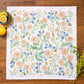 Floral patterned towel on a wooden surface with lemons and a bowl.