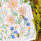 Floral patterned towel with flowers and bees on a wooden surface