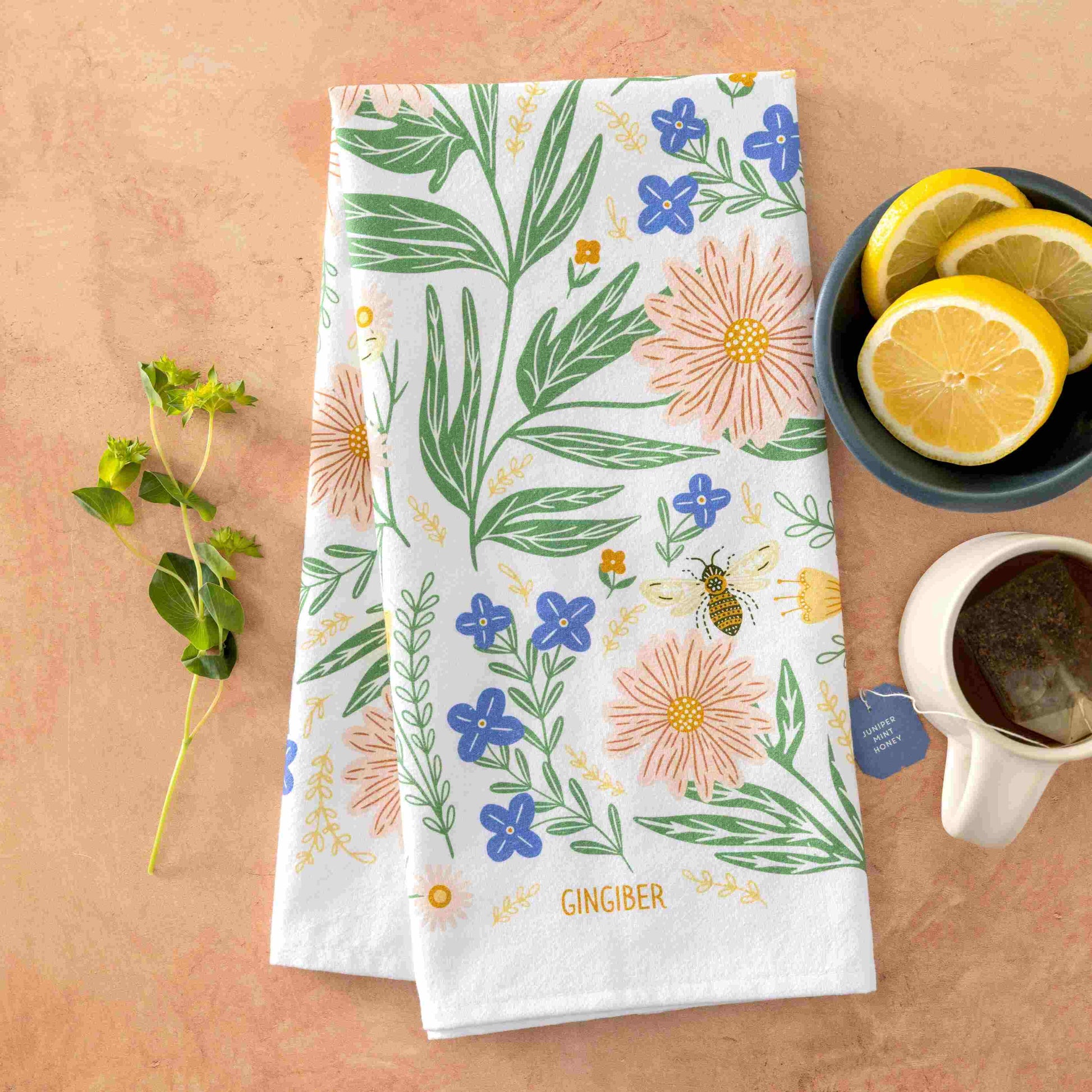 Floral patterned towel on a wooden surface with a cup of tea and lemon slices.
