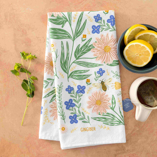 Floral patterned towel on a wooden surface with a cup of tea and lemon slices.