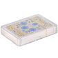 Playing cards with floral design in a transparent box on a white background