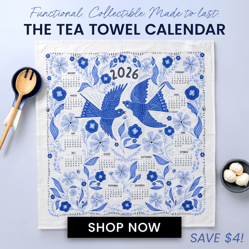 Tea towel with 2026 calendar featuring blue birds and flowers, displayed on a kitchen counter.