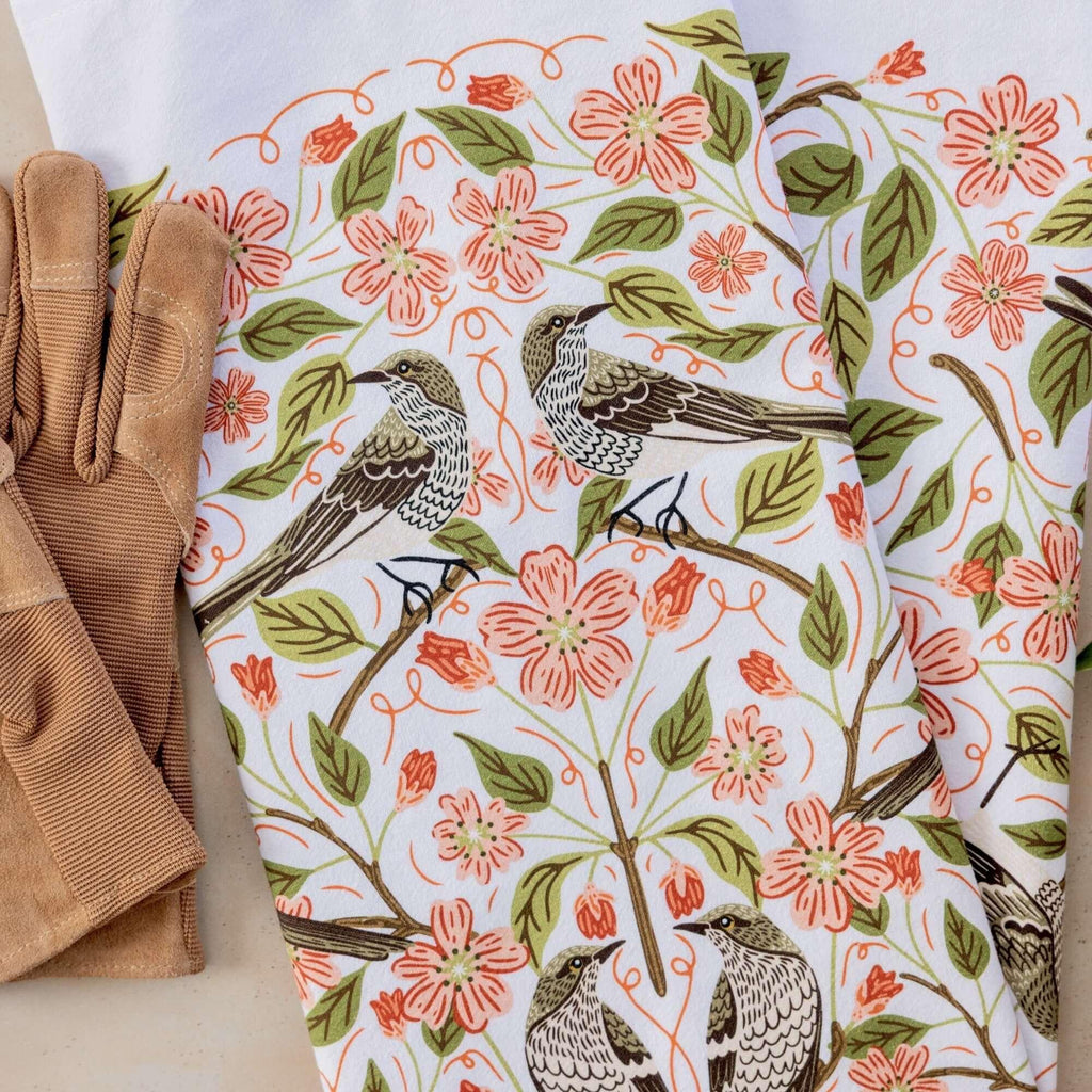 Floral and bird patterned fabric with brown gloves on a white background