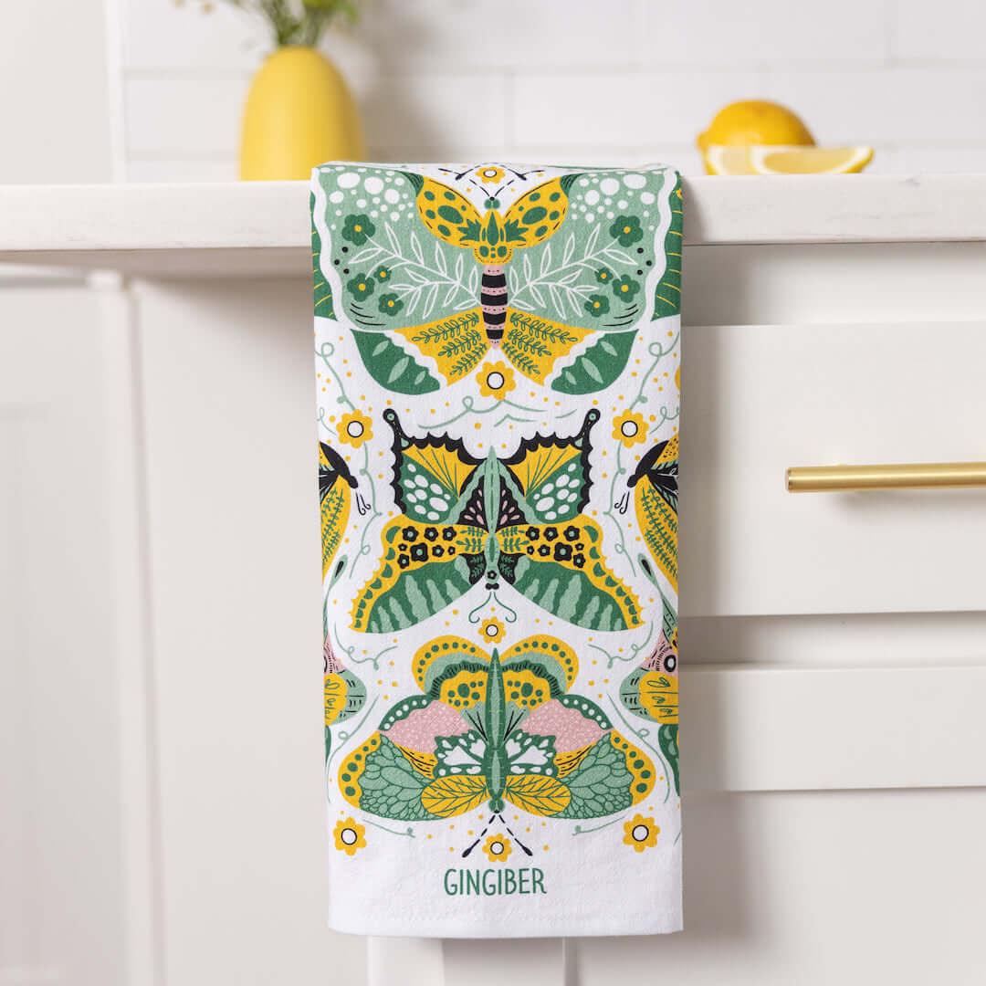 Colorful butterfly patterned towel hanging on a kitchen cabinet.