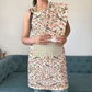 Apple Blossom Apron and Tea Towel Bundle - person wearing floral apron and matching tea towel bundle with checkered pocket, indoor setting