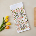 Floral and bird patterned towel with yellow tulips on a beige surface