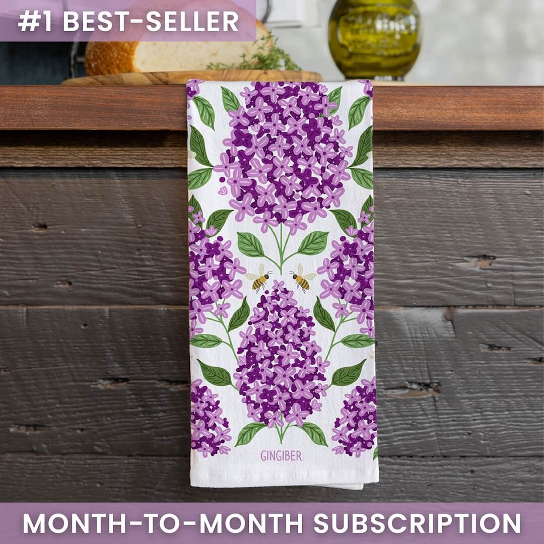 Towel with purple floral design on a wooden surface, featuring the brand 'Gingiber'.