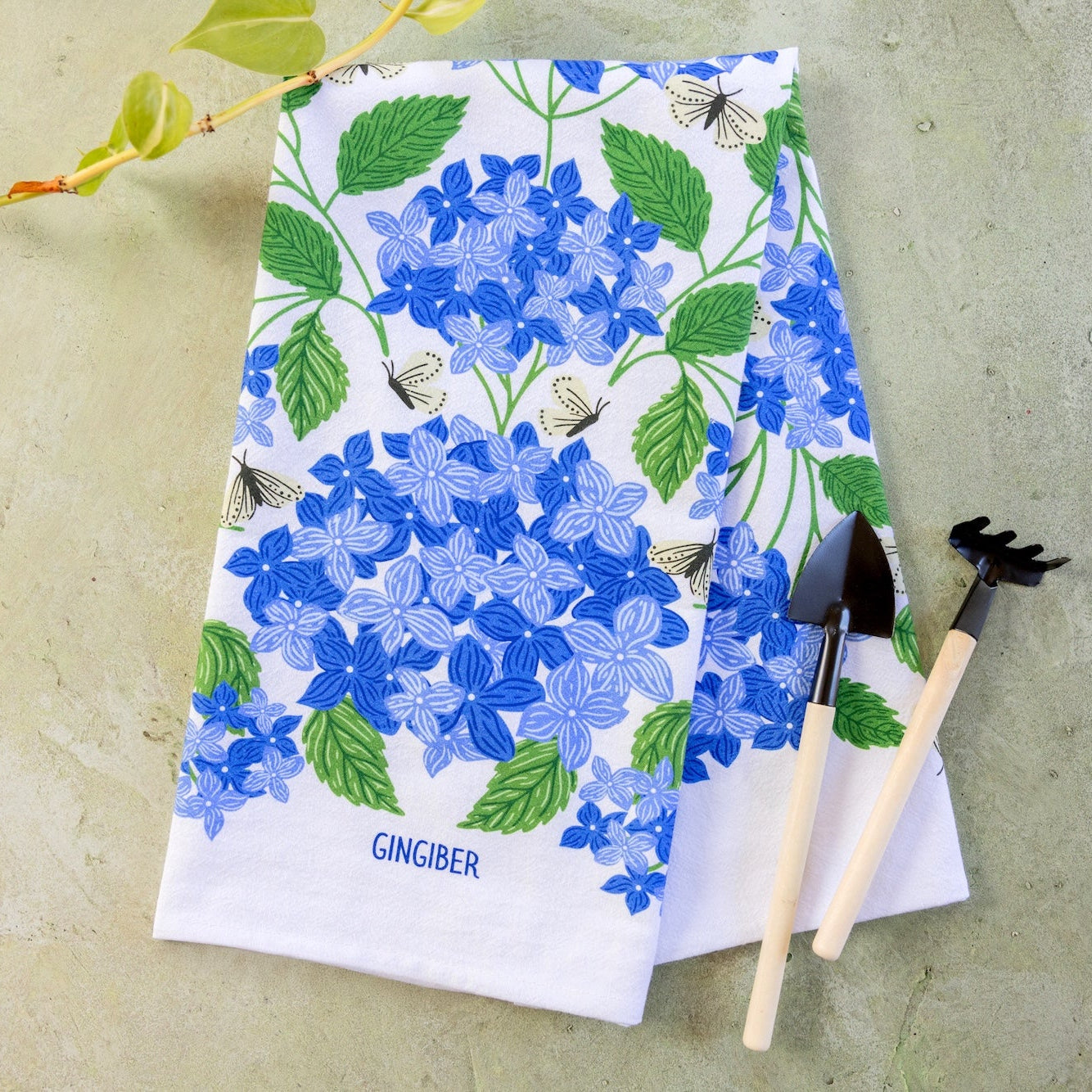Floral patterned towel with gardening tools on a concrete surface
