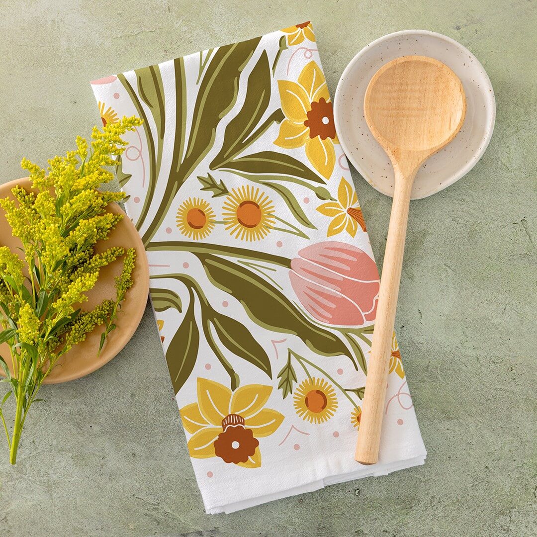 Floral patterned towel with wooden spoon and plate on a green surface