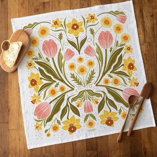 Floral patterned towel on a wooden surface with wooden spoons and a heart-shaped object.
