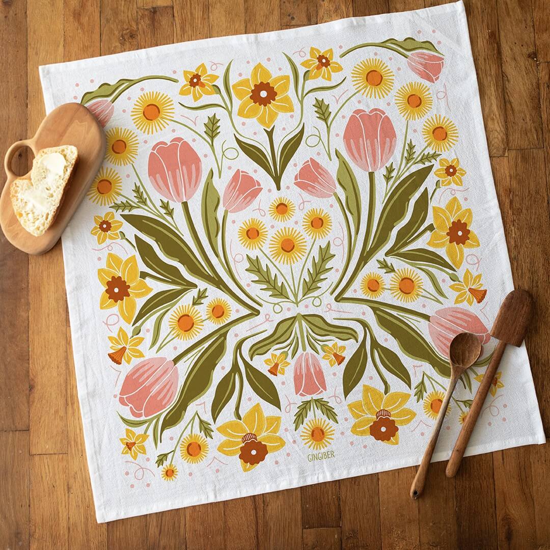 Floral patterned towel on a wooden surface with wooden spoons and a heart-shaped object.