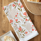 Floral and swan patterned towel on a wooden table with bread and a plate.