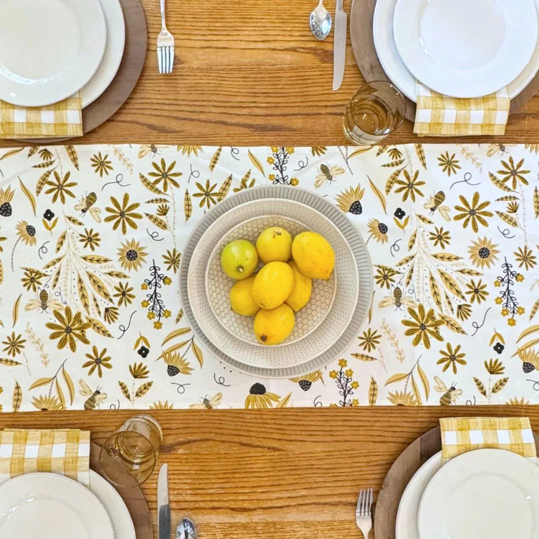 bundle of tabletop products - white table runner with bee and floral elements, gold gingham cloth napkins