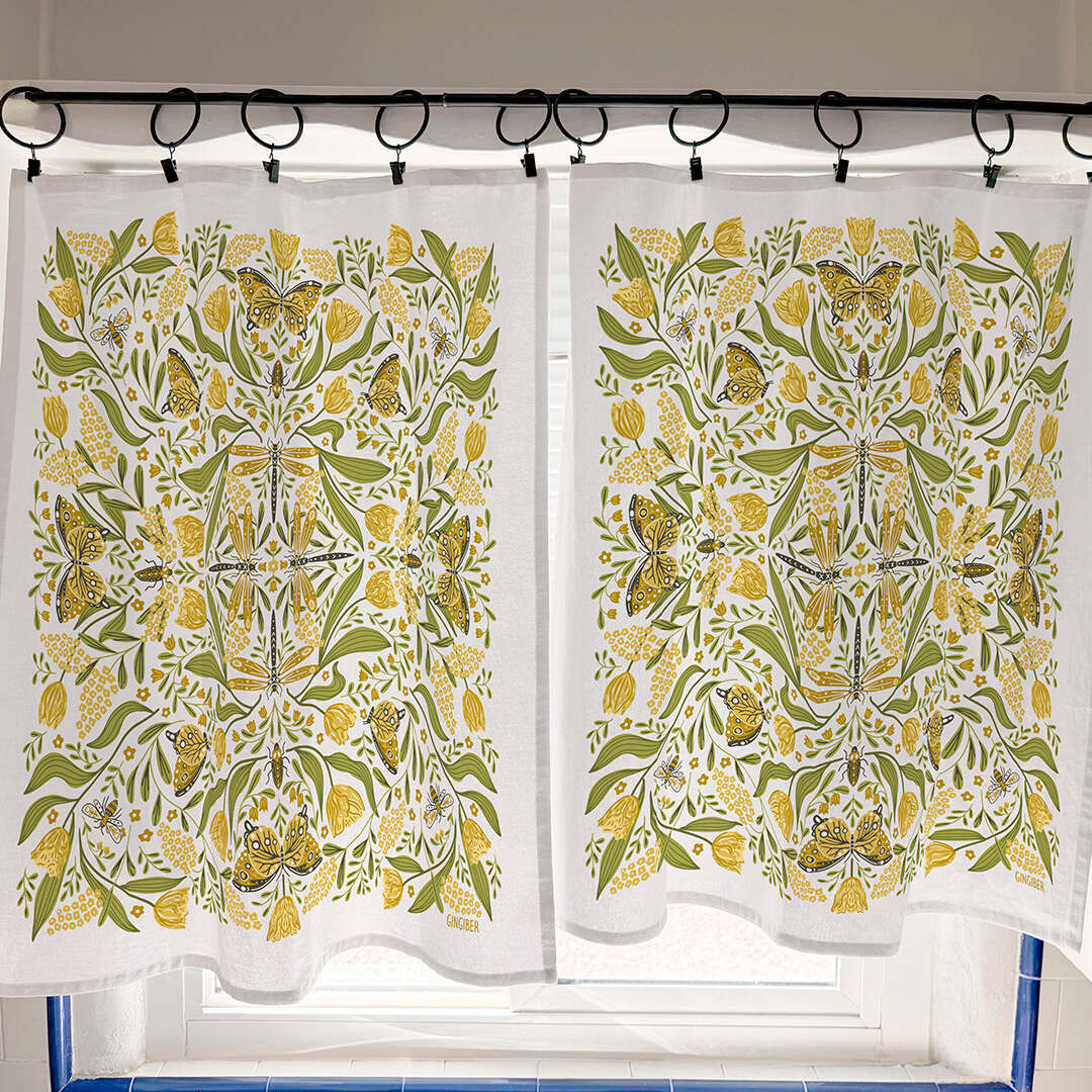 Pair of patterned curtains with yellow and green design on a rod.
