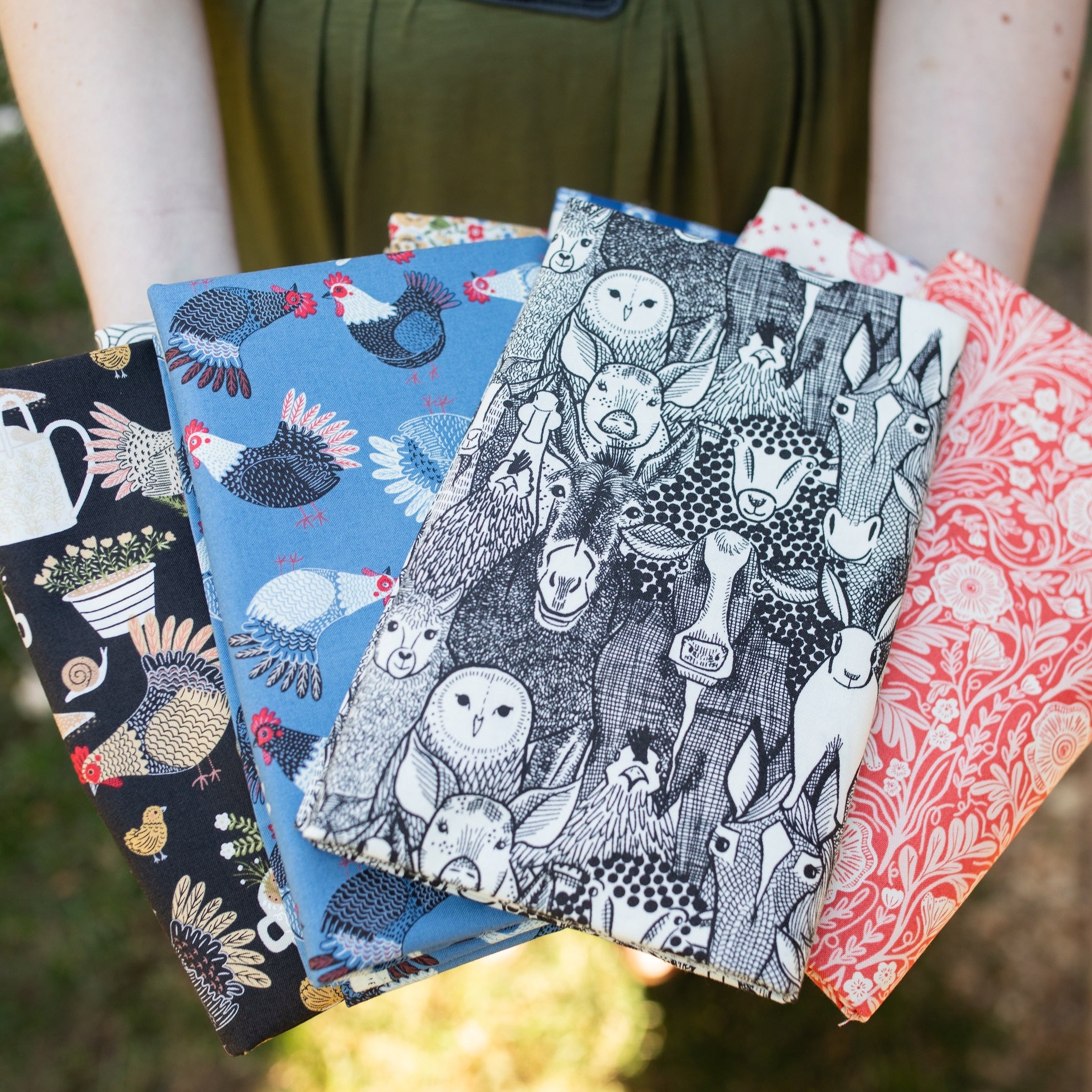 Four patterned books held by a person outdoors
