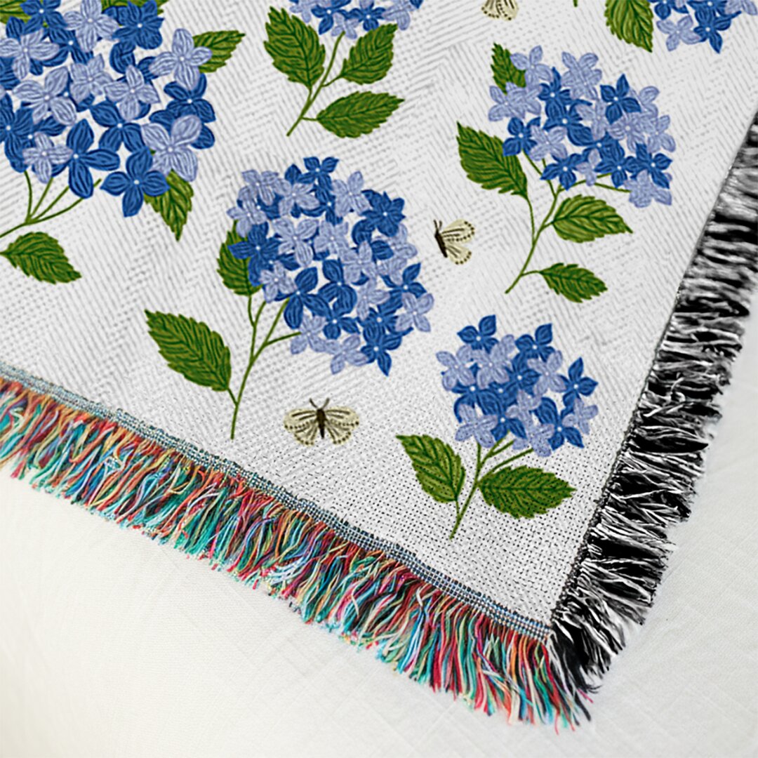 Floral patterned blanket with blue flowers and green leaves on a white background