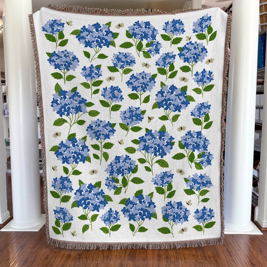 Floral-patterned blanket with blue flowers and green leaves on a wooden floor.