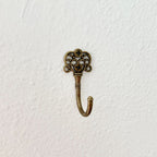 Decorative brass hook with intricate design on a white background
