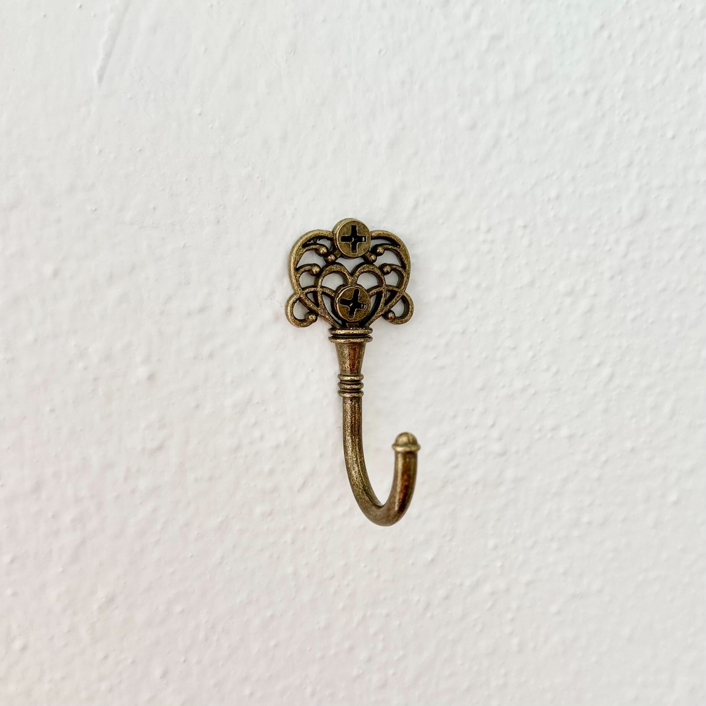 Decorative brass hook with intricate design on a white background