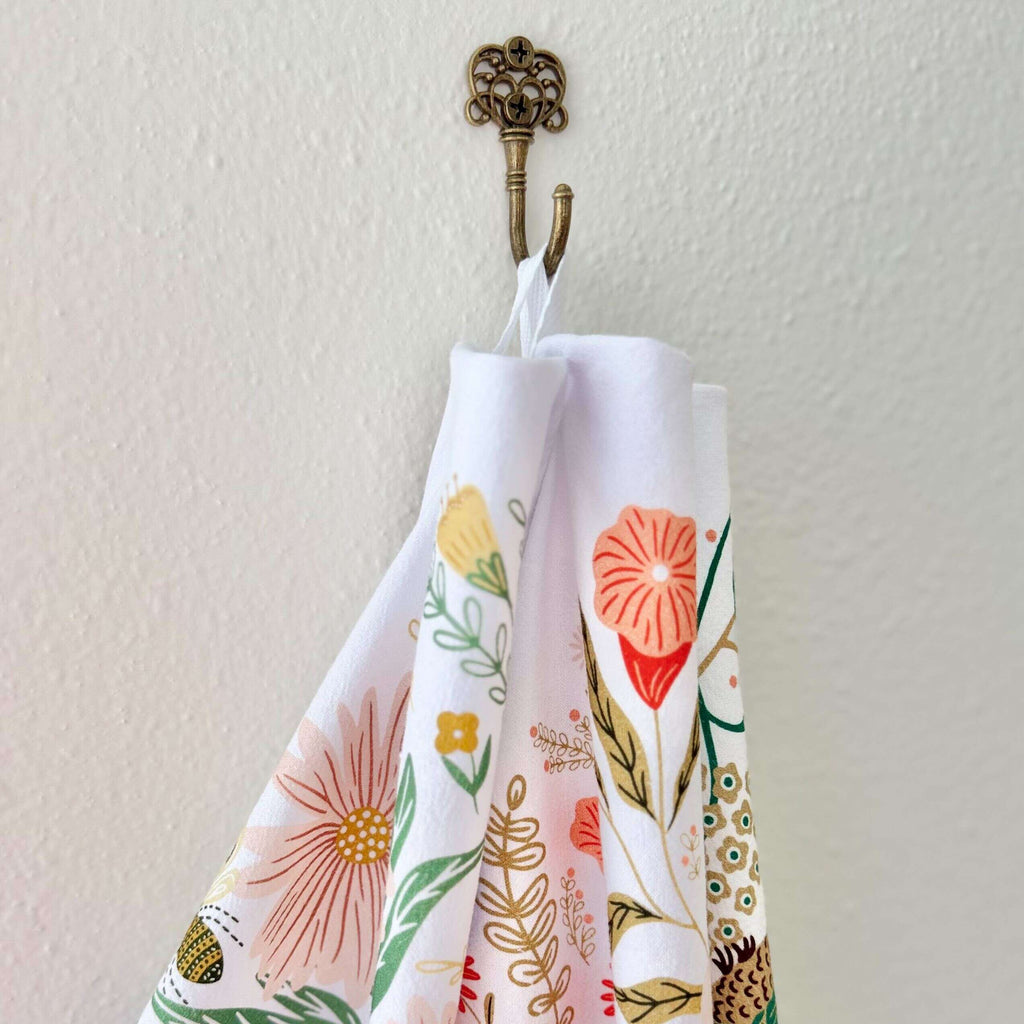 Floral-patterned towel hanging on a decorative hook against a light background