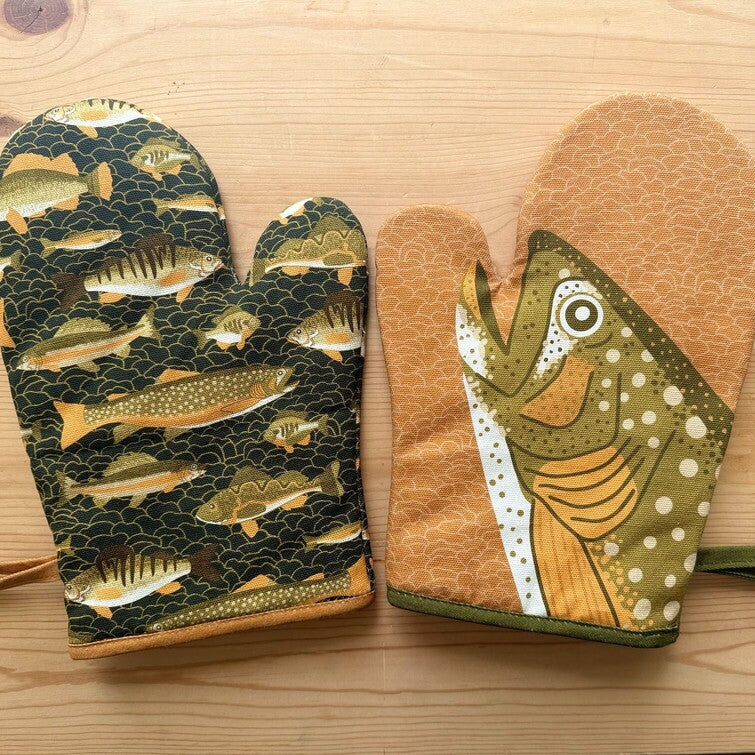 Pair of oven mitts with fish pattern on a wooden surface