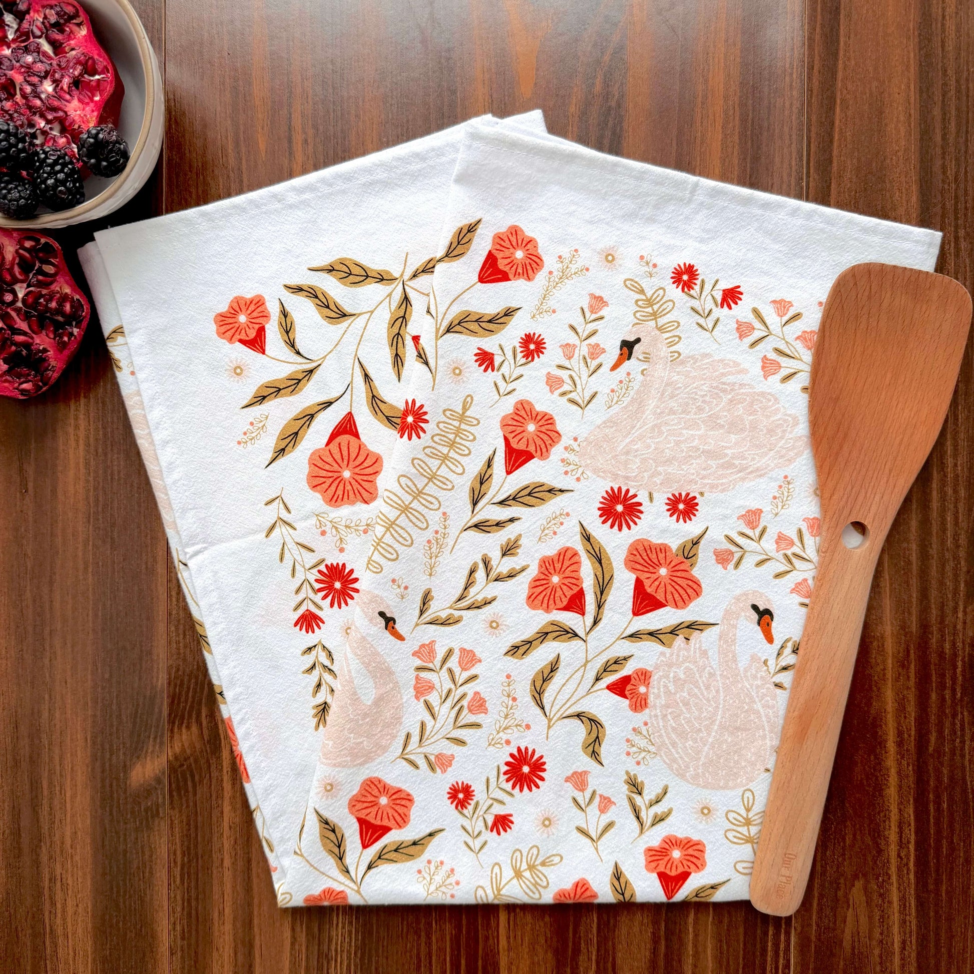 Floral-patterned kitchen towel with a wooden spatula on a wooden surface