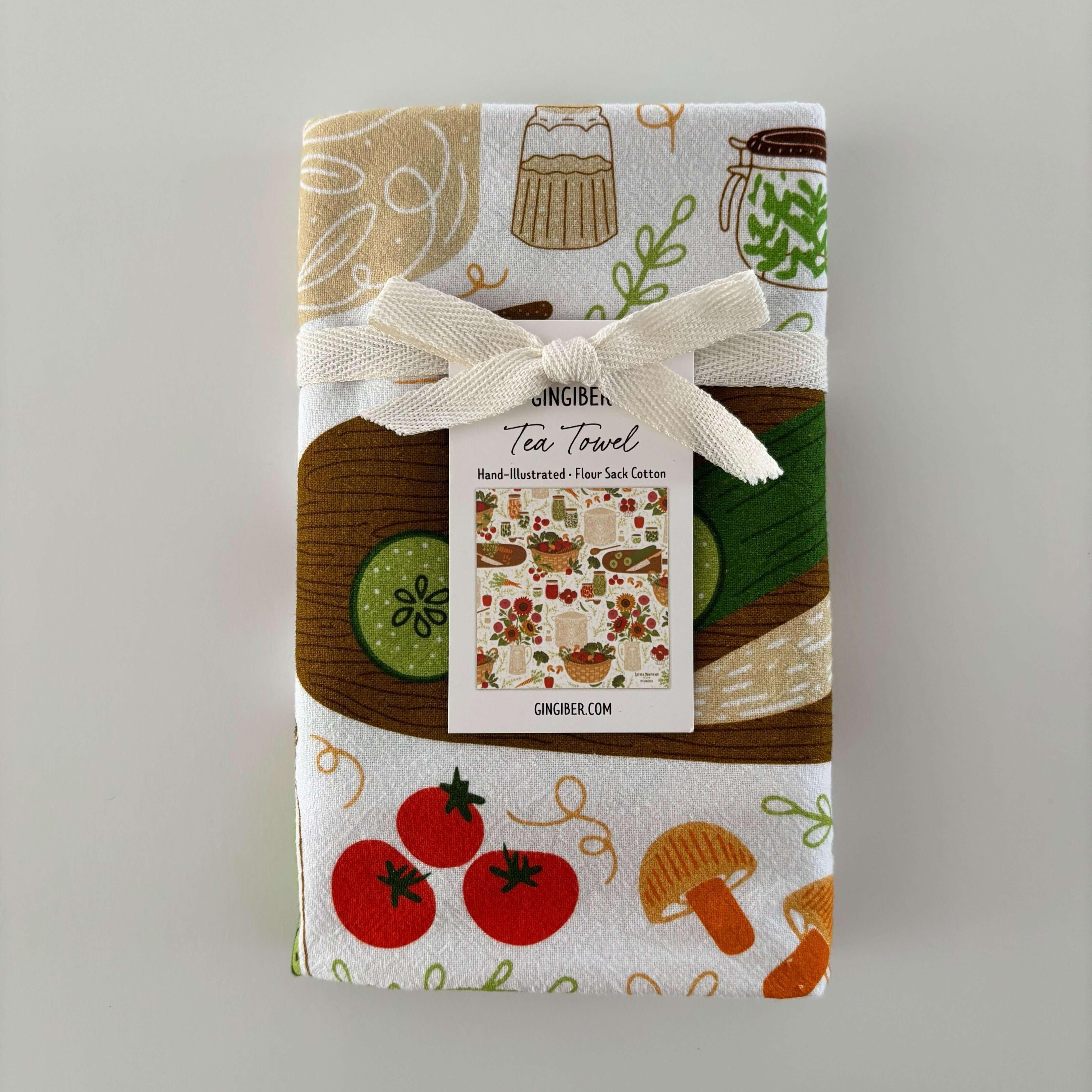 Packaged tea towel with food-themed design on a gray background