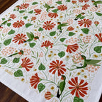 Decorative tablecloth with floral and hummingbird pattern on a wooden surface