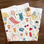 Folded towel with summer-themed designs on a wooden surface