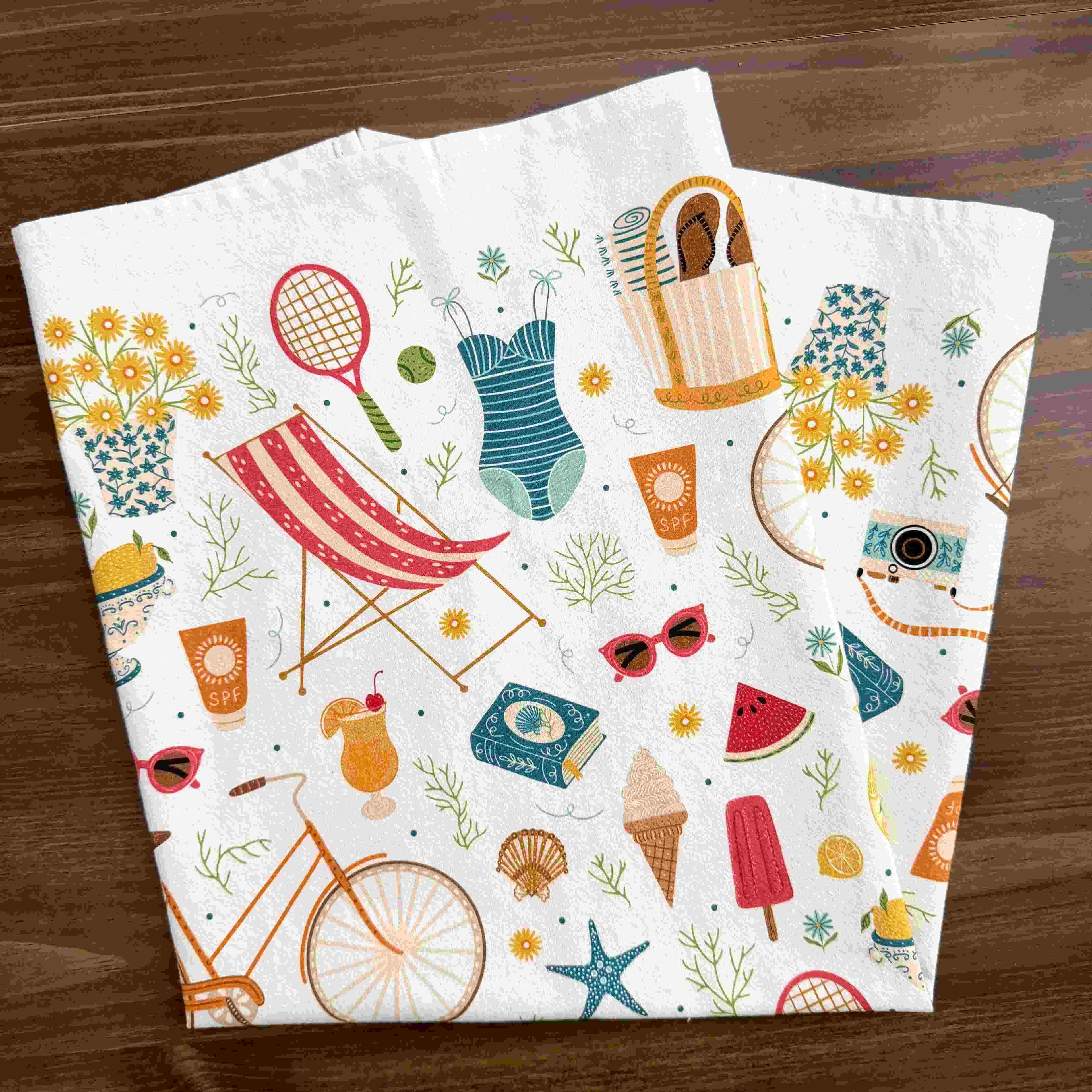 Folded towel with summer-themed designs on a wooden surface