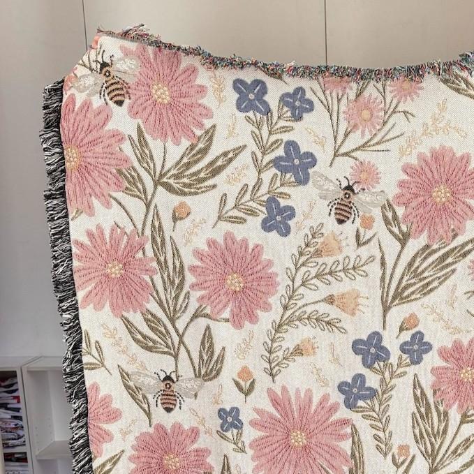 Floral patterned blanket with pink flowers and bees on a white background